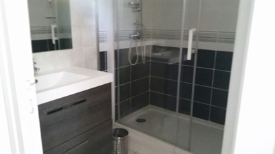 Grande douche avec porte coulissante. Meuble deux tiroirs et grand miroir